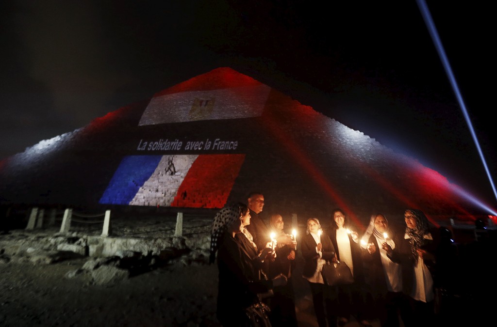 Egyptians light candles as the French and Egyptian flags and France's national colours of blue, white and red are projected onto one of the Giza pyramids, in tribute to the victims of the Paris attacks, on the outskirts of Cairo, Egypt, November 15, 2015. The words on the pyramid read: "Solidarity with France". 
